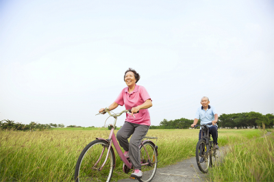 happy asian elderly senior couple biking in the park